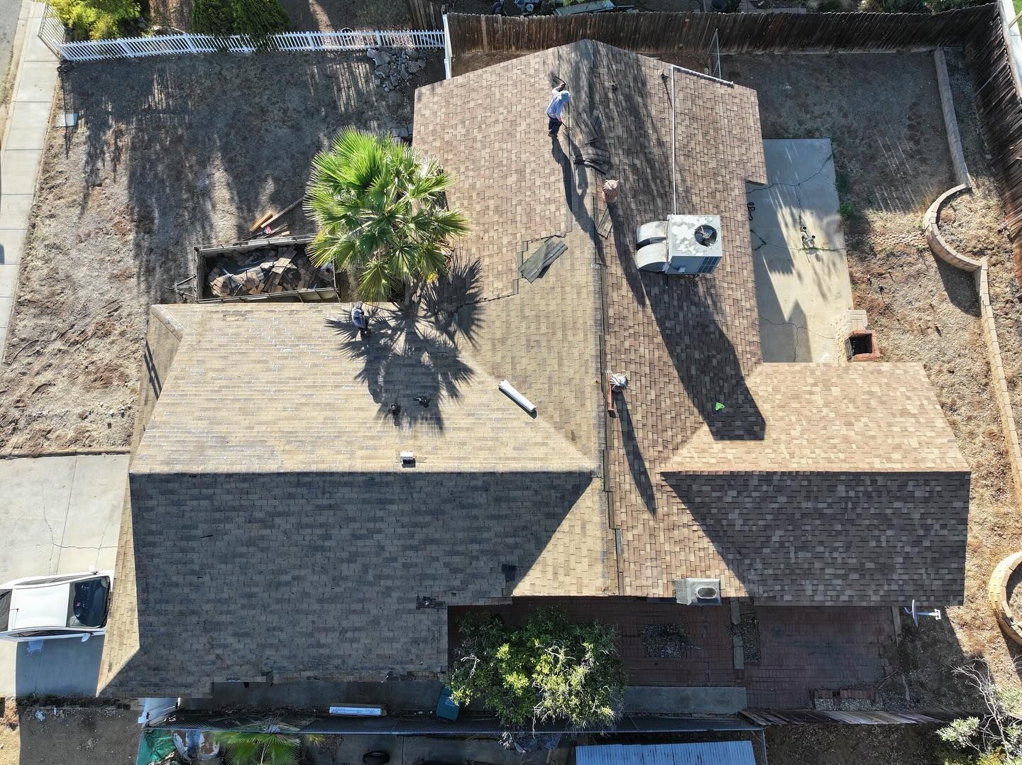 An aerial view of a house roof featuring shingles, an AC unit, and a person walking on the roof.