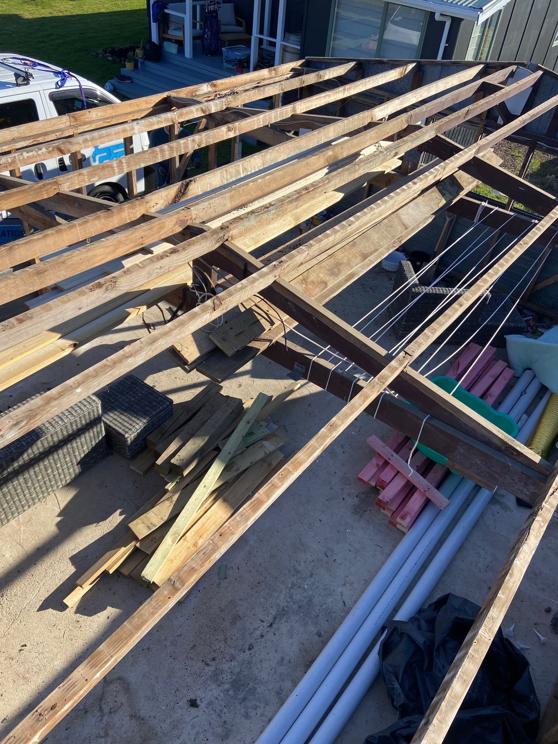 Overhead view of a partially dismantled wooden deck frame with scattered construction materials.