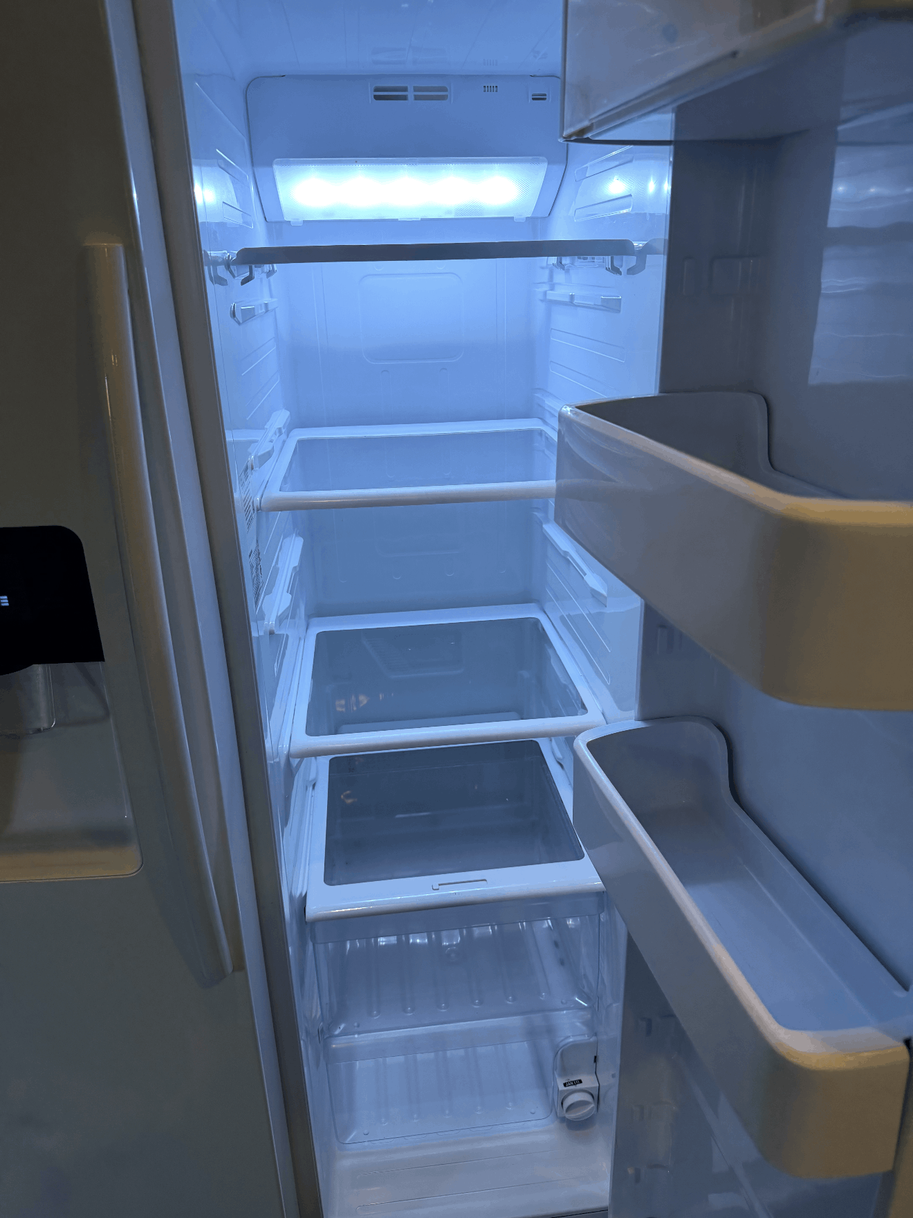 Open refrigerator with empty shelves and bright interior light
