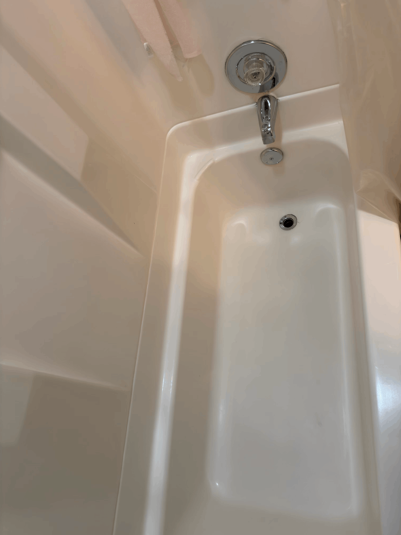 Empty white bathtub with shower faucet and drain hole visible near the top end