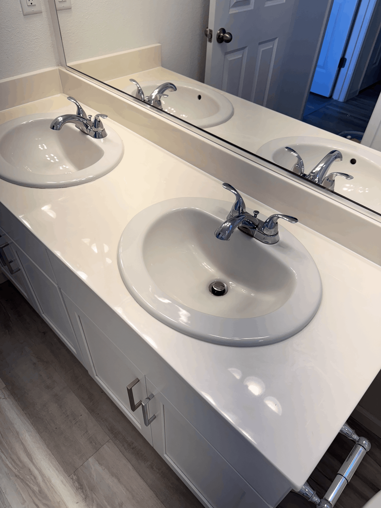 Bathroom vanity with two white sinks, chrome faucets, and a large wall mirror above.