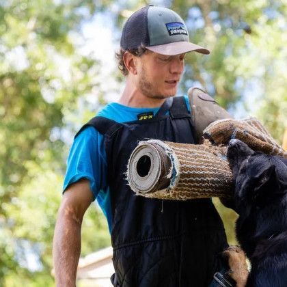 A man wearing a patagonia hat is holding a piece of wood.