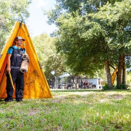 A man is standing in front of a yellow tent in a park.