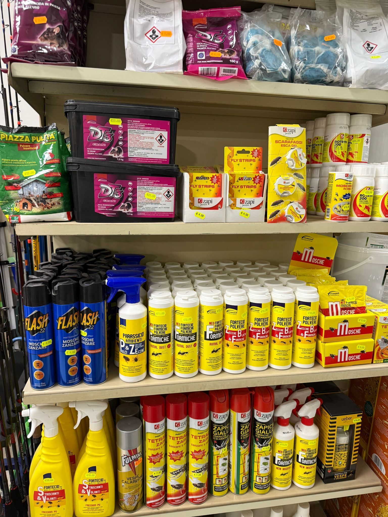 Scaffali di un negozio riforniti con vari prodotti per la pulizia della casa, spray repellenti per insetti e flaconi.