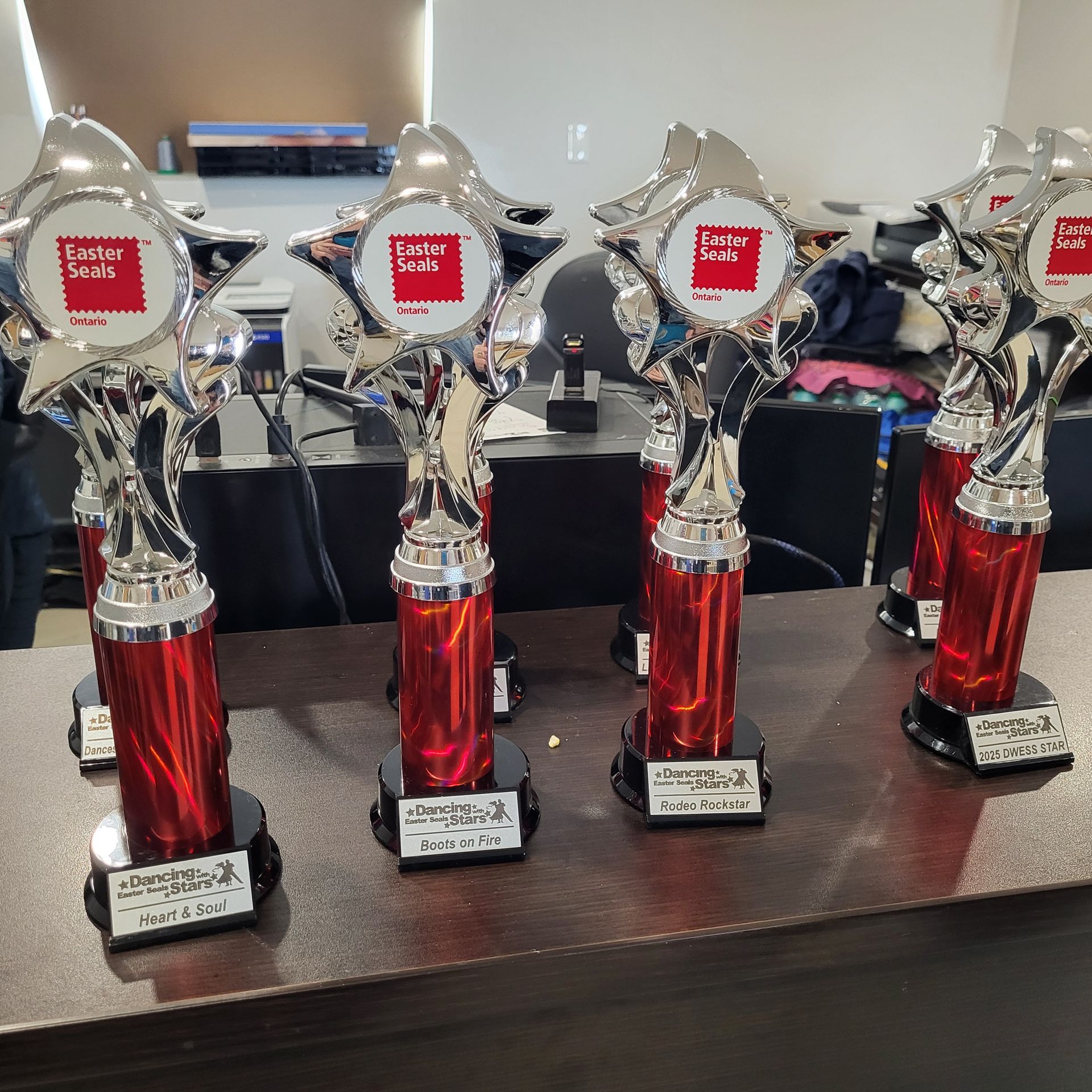 Silver and red trophies with logos on a table.