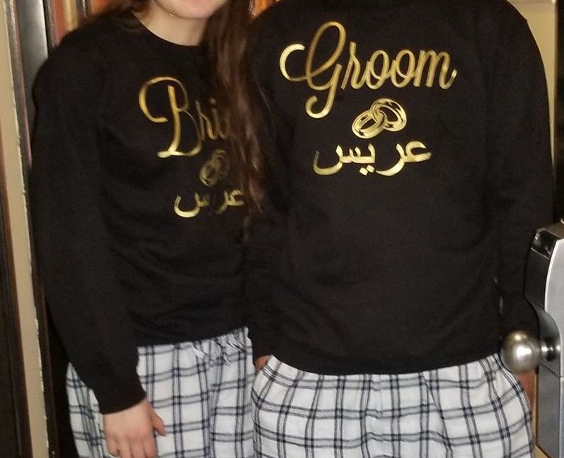 Two people wearing black sweatshirts with gold