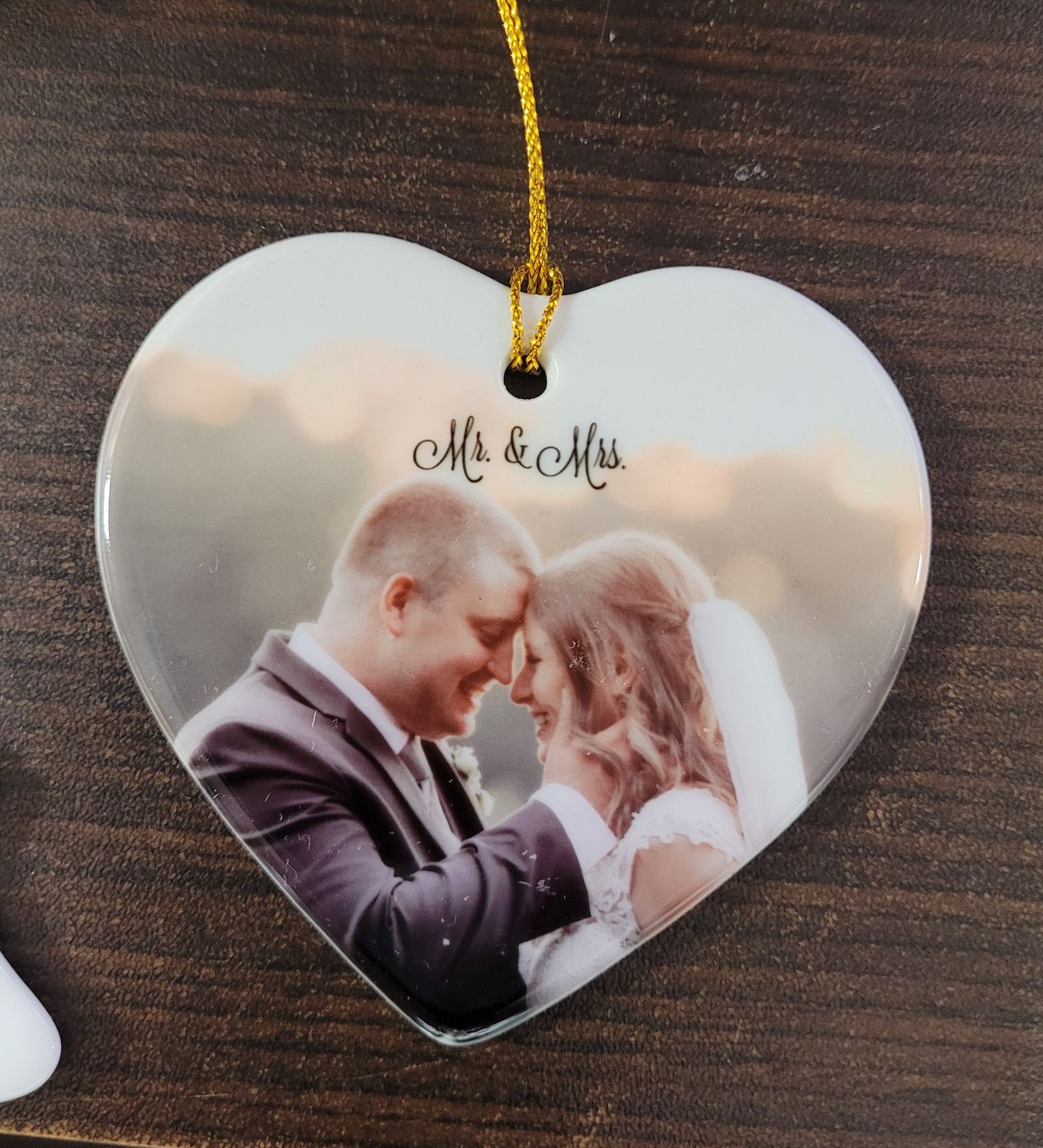 Heart-shaped ornament with wedding photo; couple touching foreheads.