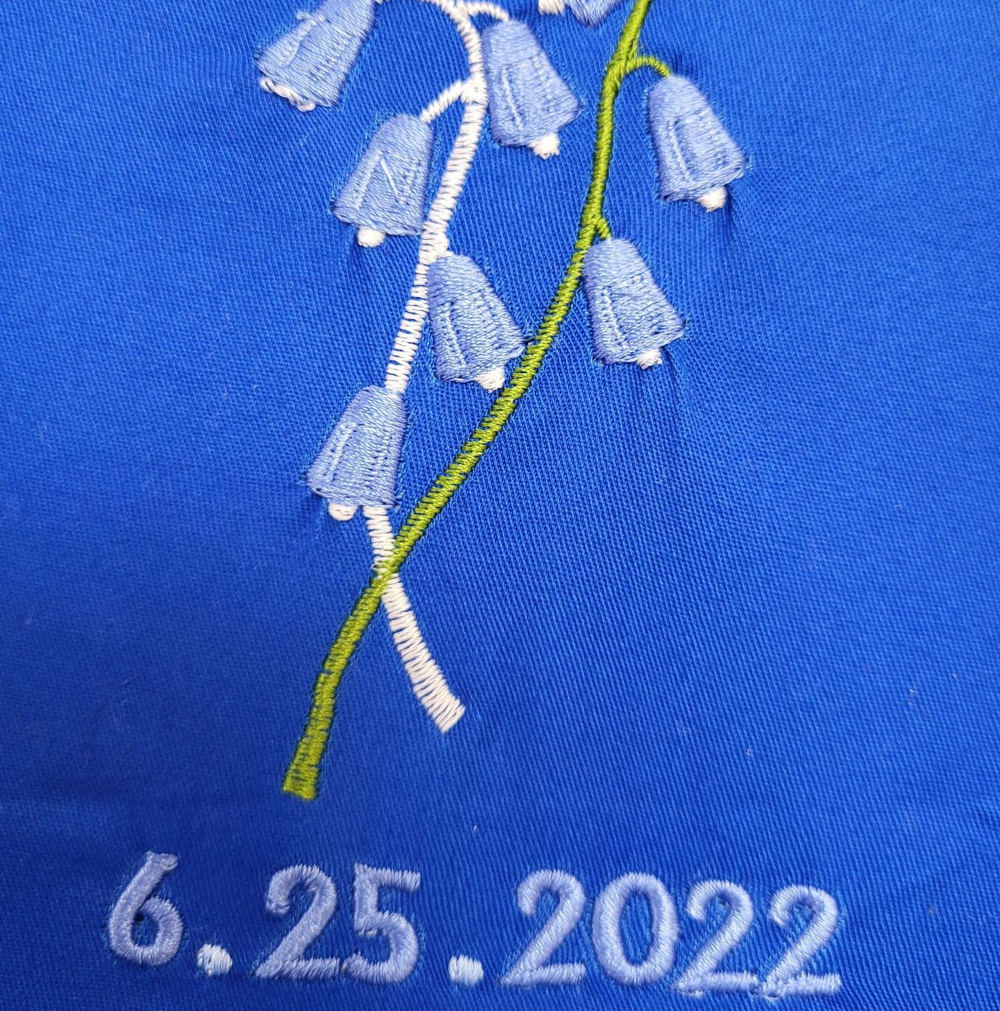 Blue embroidered flower stem with date