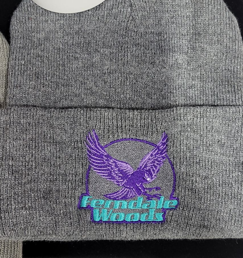 Gray beanie with embroidered purple eagle logo inside a circle and the words 