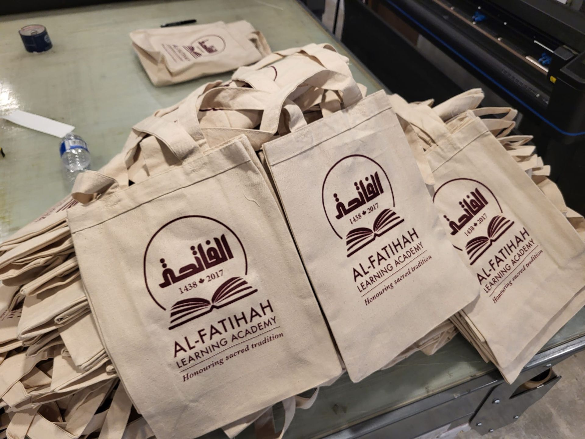 A pile of beige tote bags printed with the