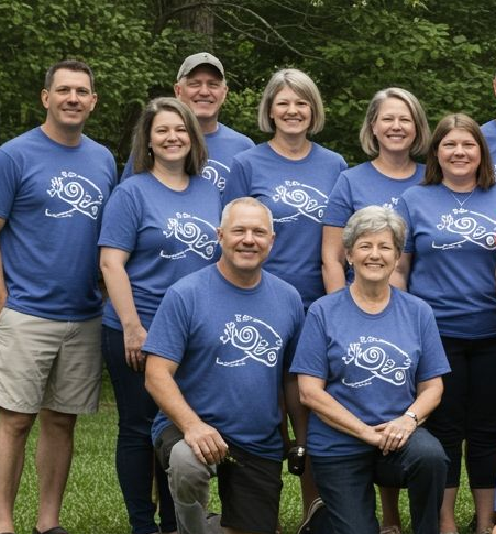 Group of people in blue t-shirts pose outdoors.