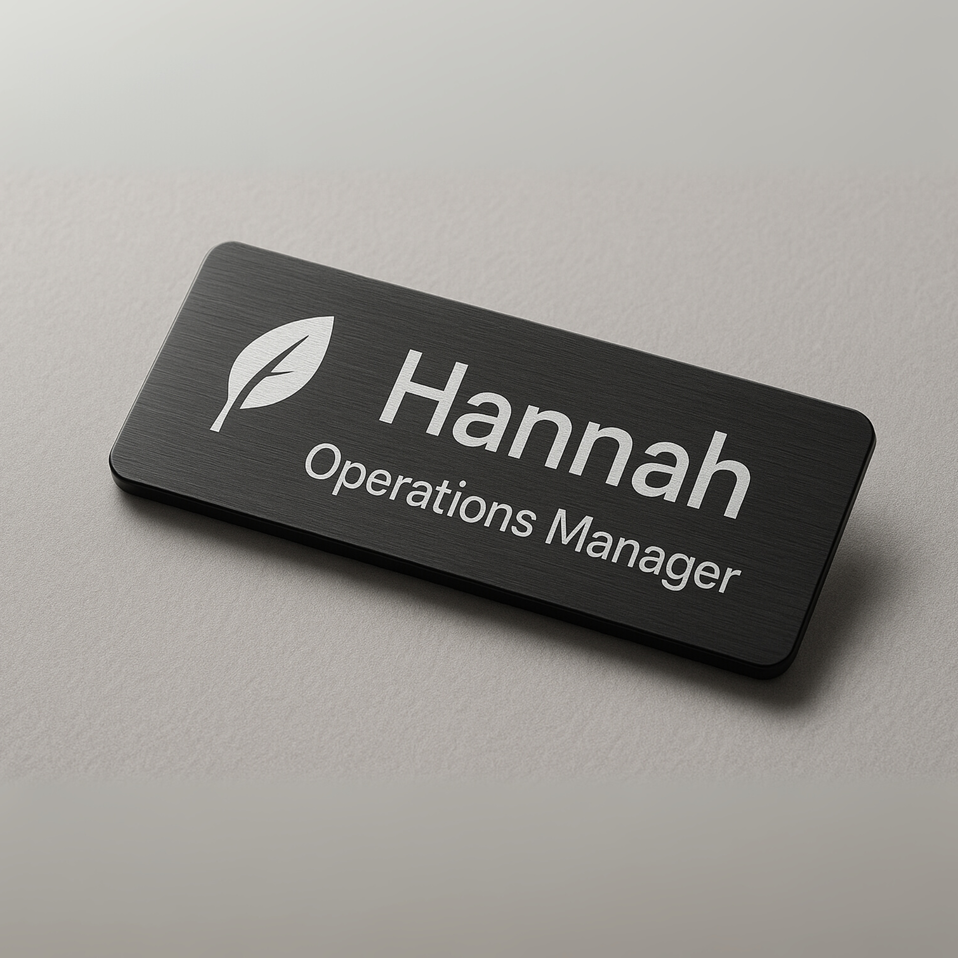 Black name tag with a leaf logo and the name