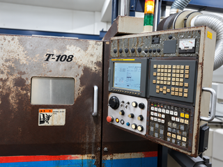 金屬 CNC 機台上標示為 T-108 的工業機械控制面板,配有顯示器和按鈕