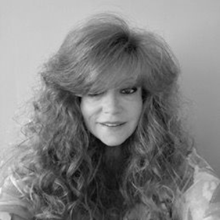 Black-and-white portrait of a person with long curly hair and a soft smile