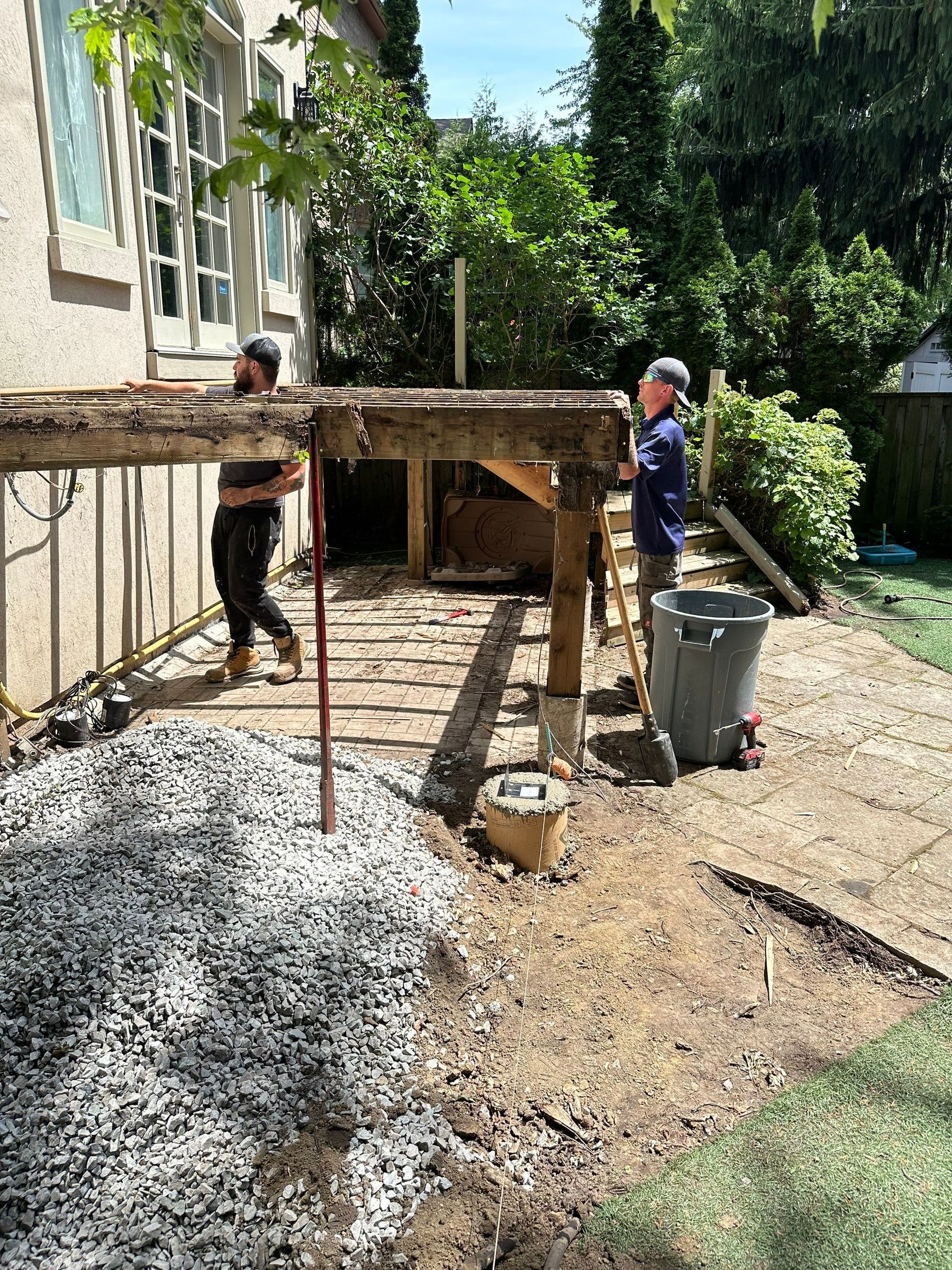 Two men are working on a deck in a backyard.