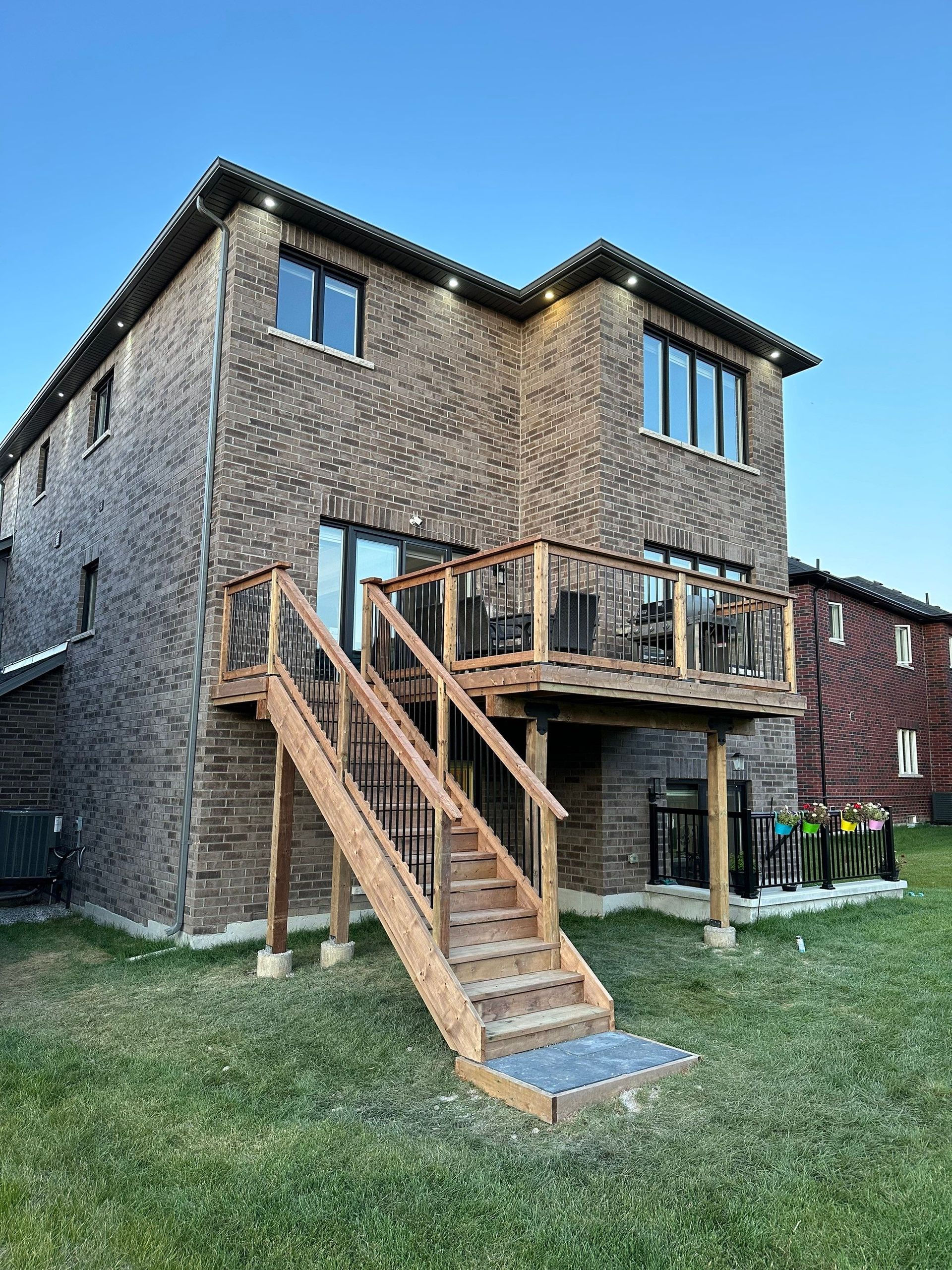 The back of a brick house with a wooden deck and stairs.