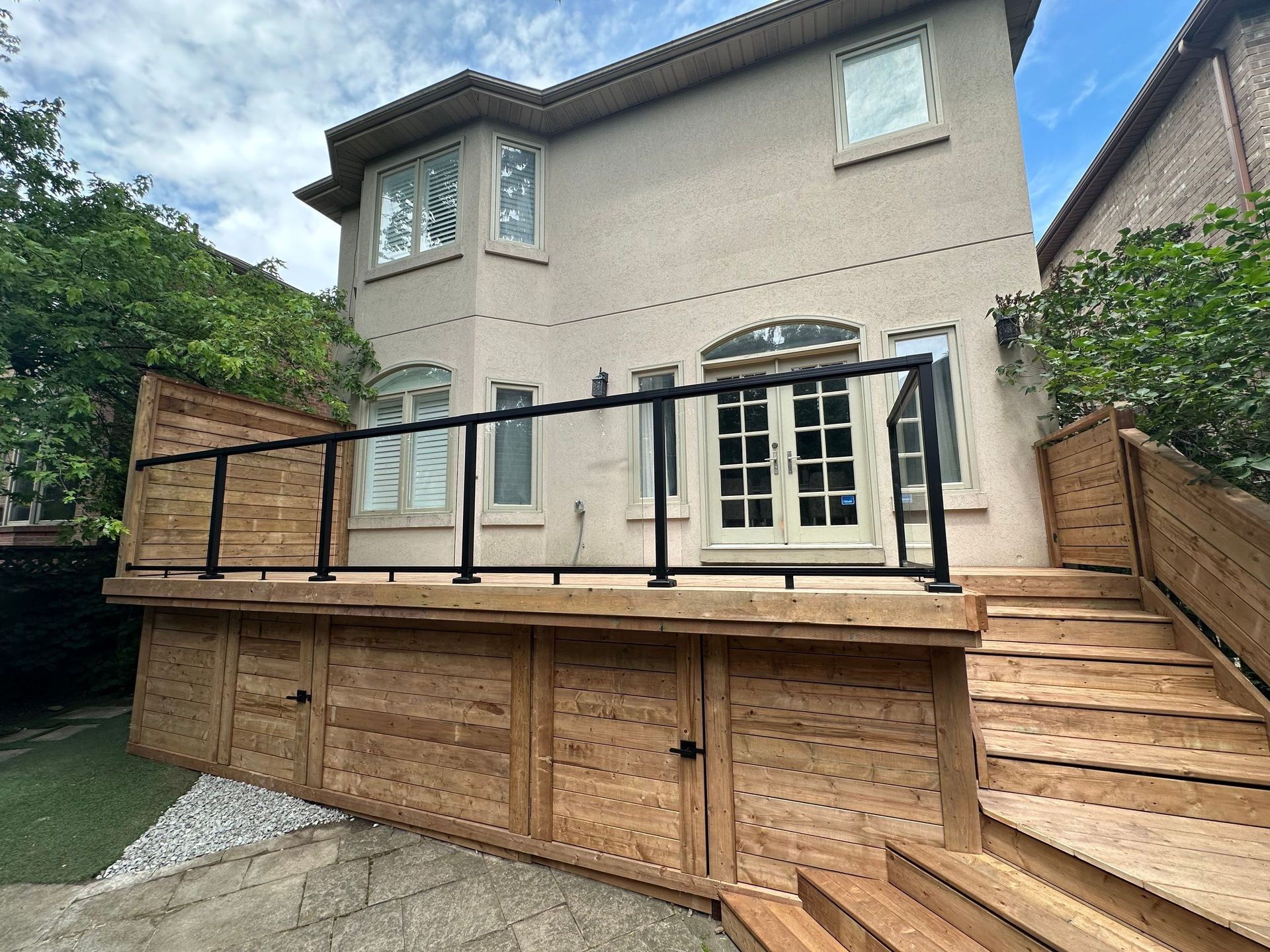 A large house with a wooden deck and stairs in front of it.