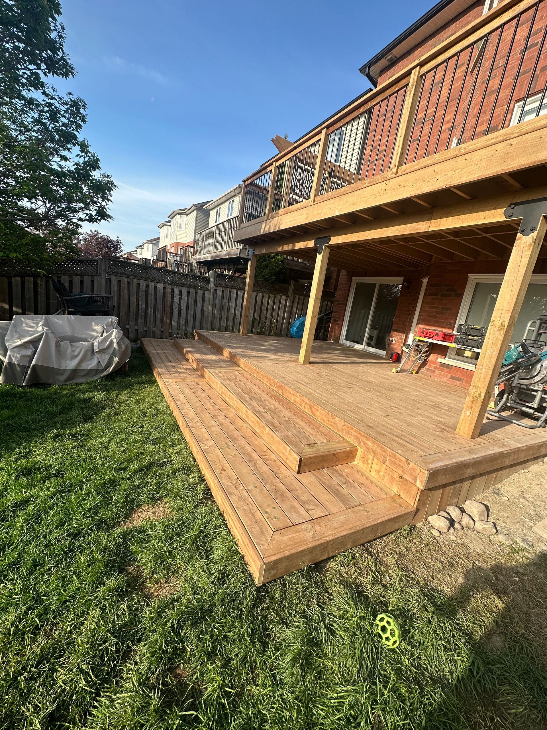 A wooden deck is being built in the backyard of a house.