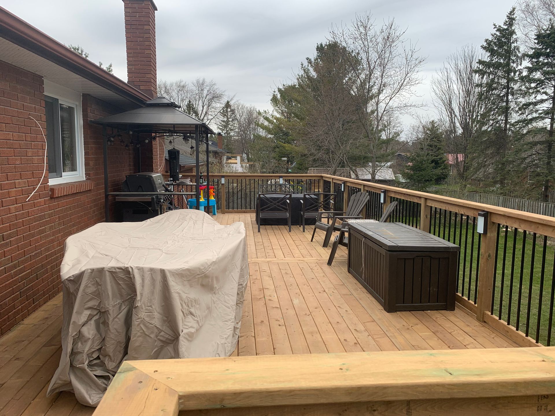 A wooden deck with a table and chairs on it in front of a brick house.