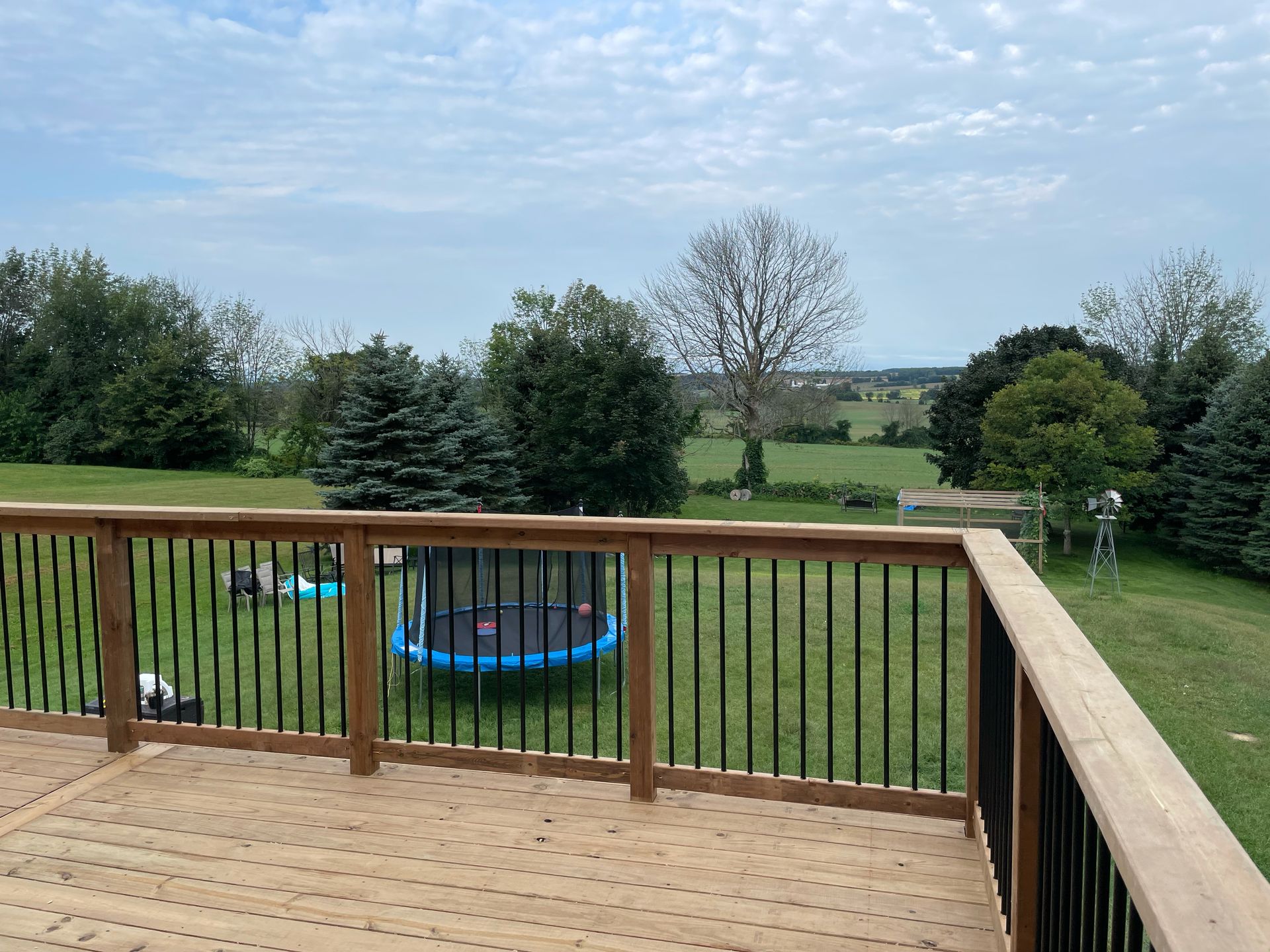 A wooden deck with a trampoline in the backyard.