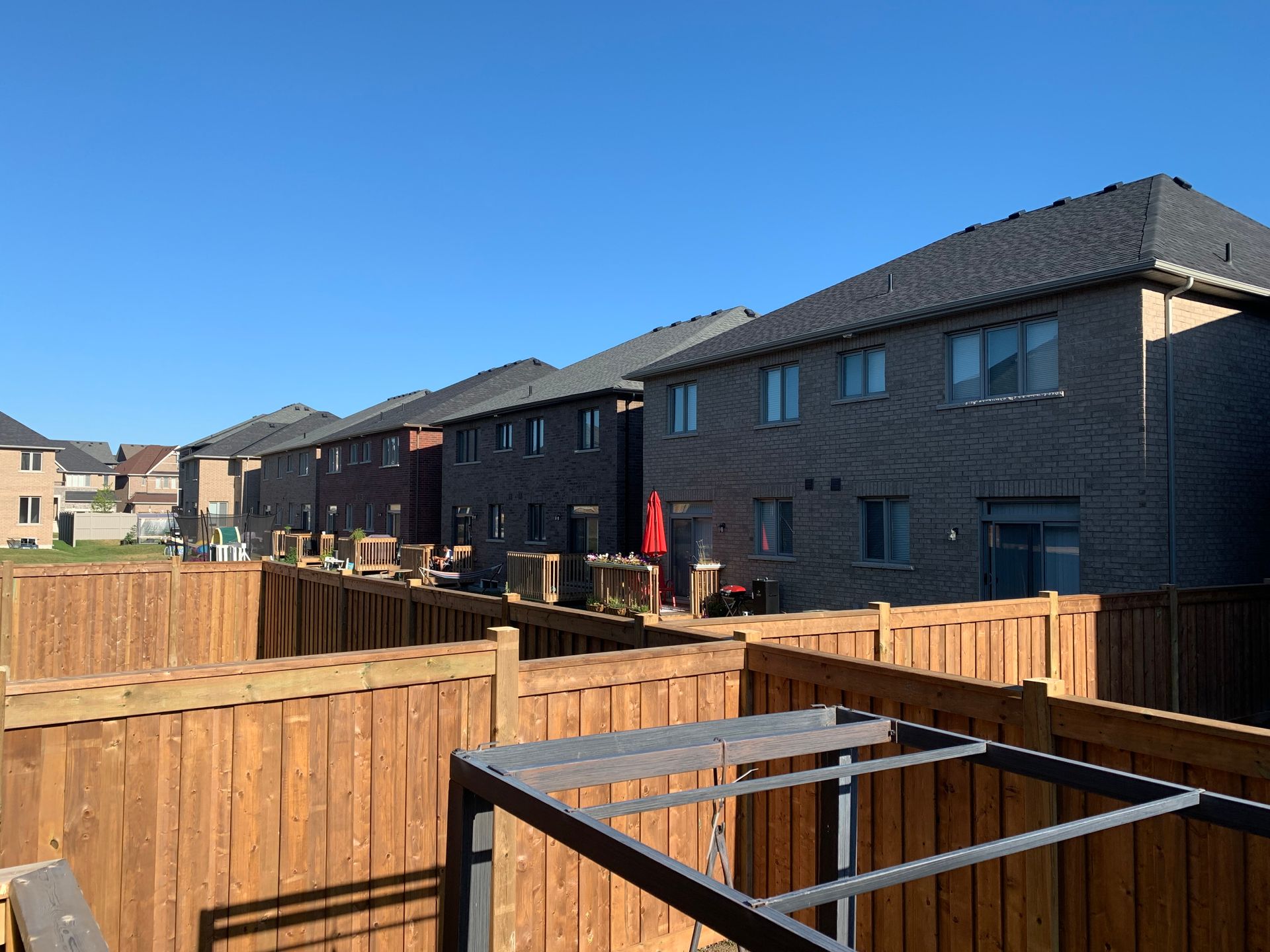 A wooden fence surrounds a row of houses in a residential area.