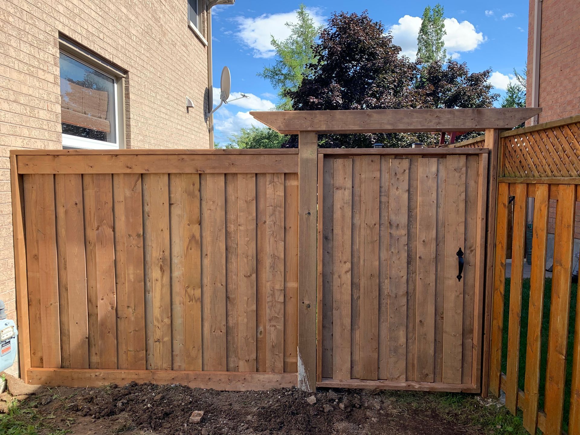 A wooden fence with a gate in the backyard of a house.