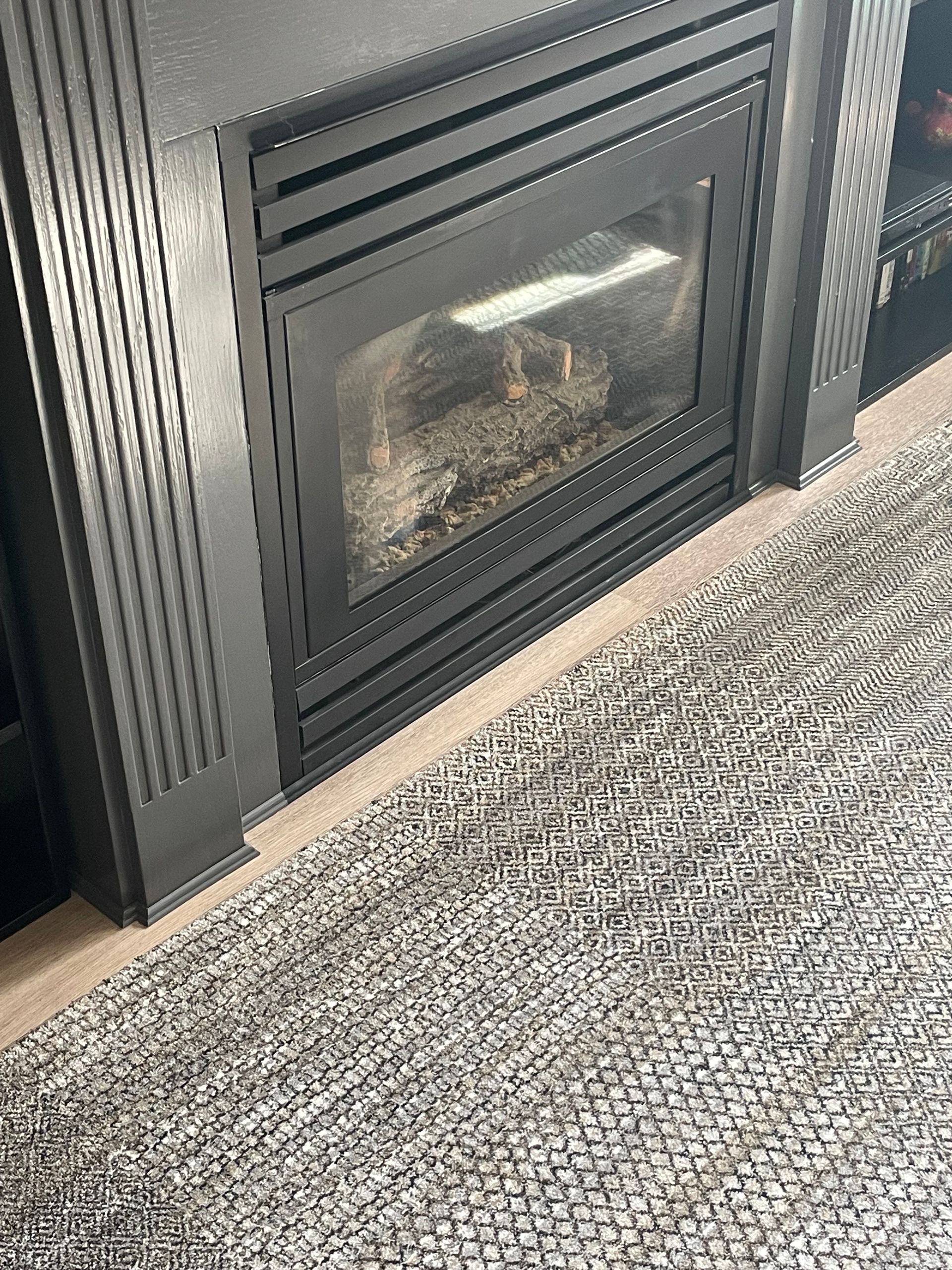 A fireplace with a rug in front of it in a living room.