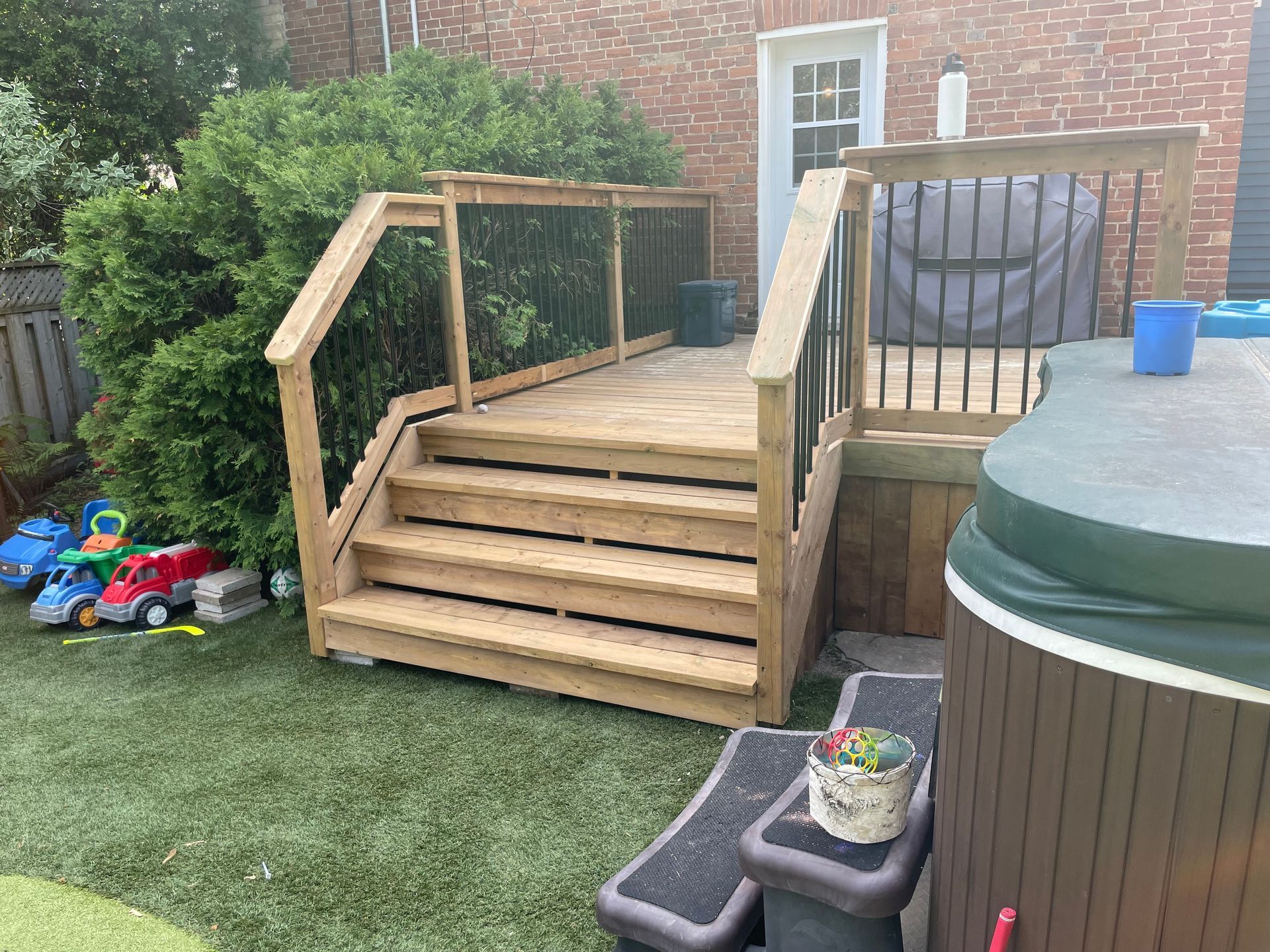 A wooden deck with stairs and a hot tub in the backyard.