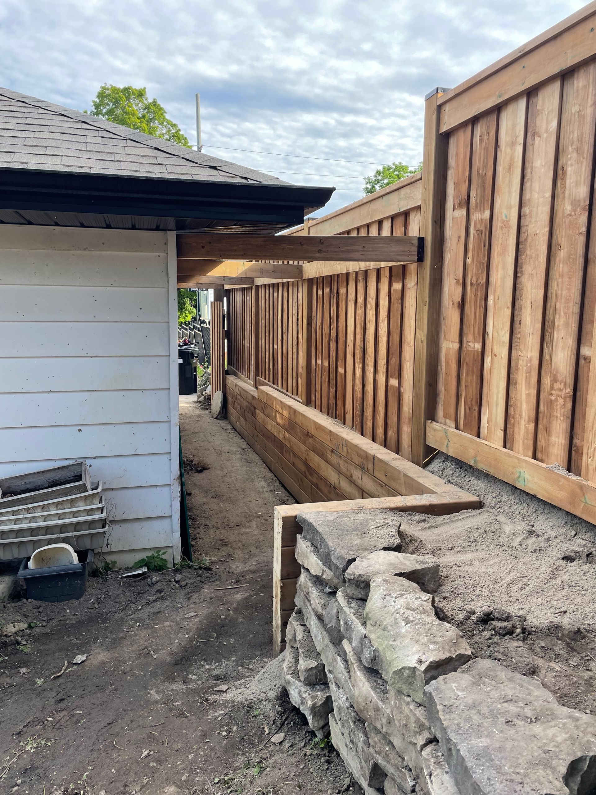 A wooden fence is being built in the backyard of a house.