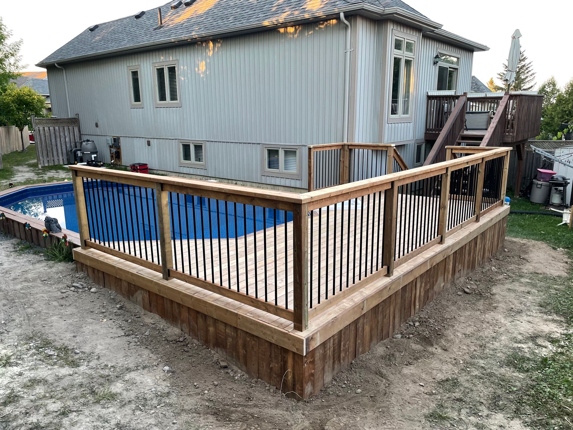 A house with a swimming pool and a wooden deck in front of it.