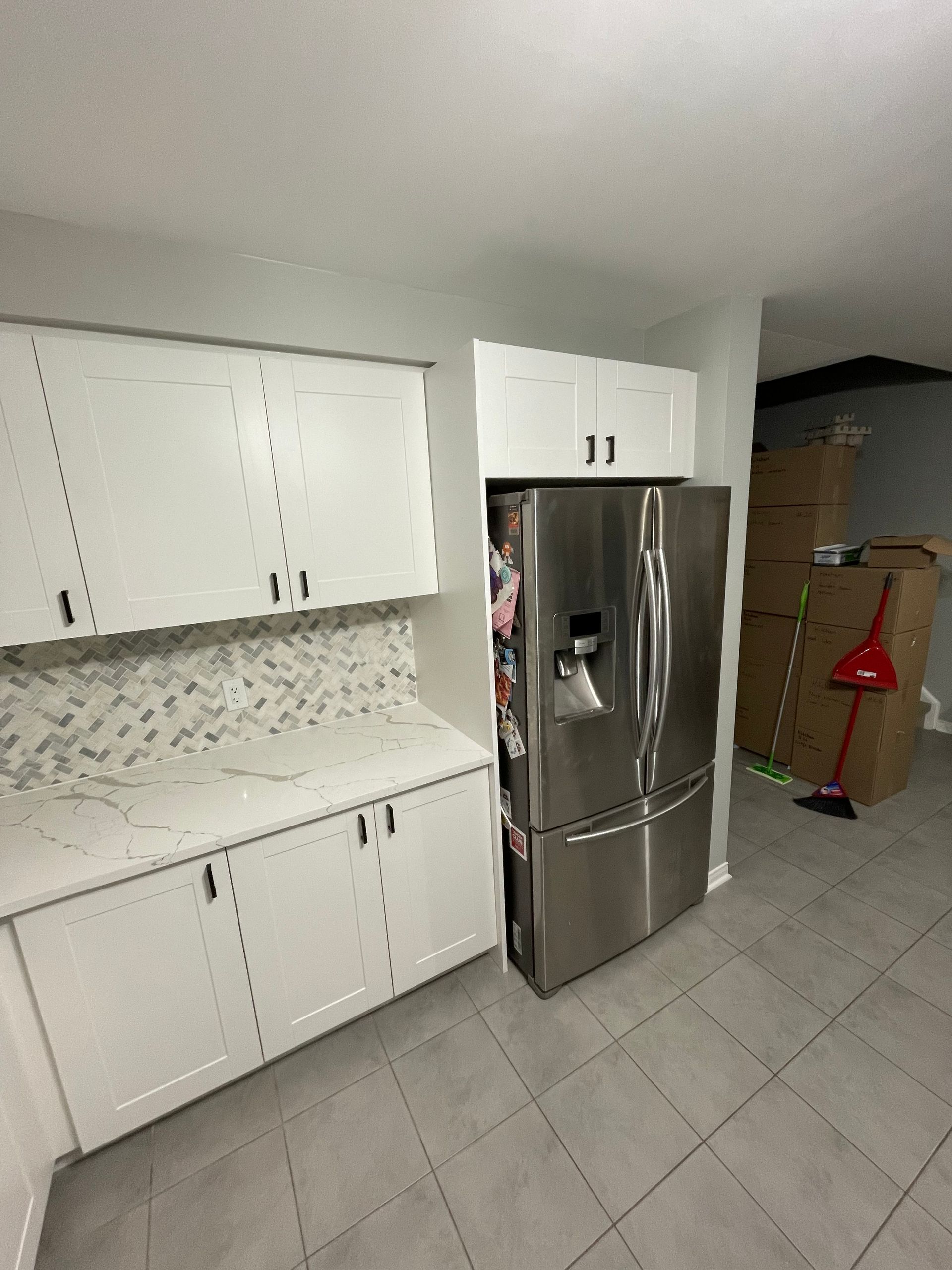 A kitchen with white cabinets and a stainless steel refrigerator