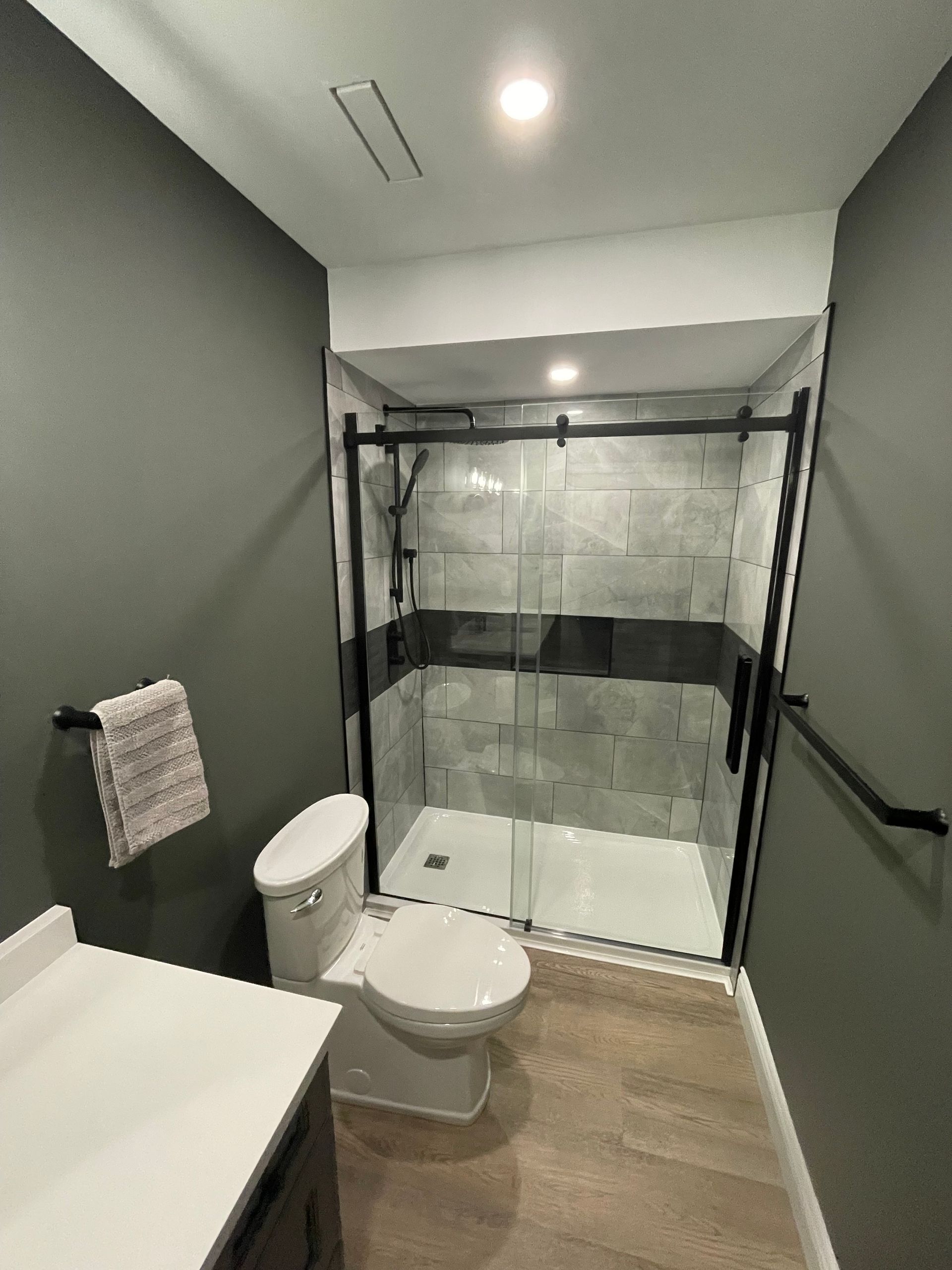 A bathroom with a toilet , sink and shower.