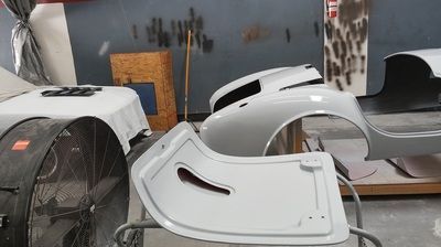 A white car is being painted in a garage