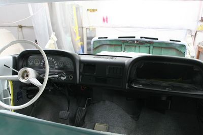 The interior of a green car with a white steering wheel and dashboard