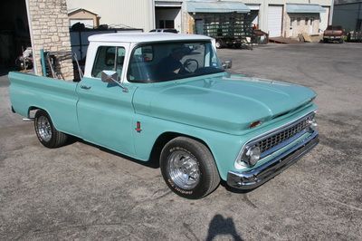 A blue and white pickup truck is parked in a parking lot