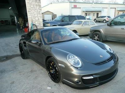 A gray porsche is parked in front of a garage