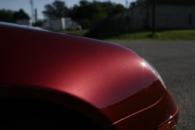 A close up of a red car 's fender on a road