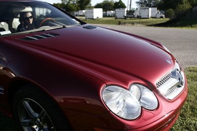 A red mercedes is parked on the side of the road