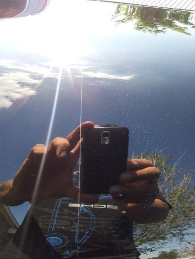 A person is taking a picture of their reflection in a car window