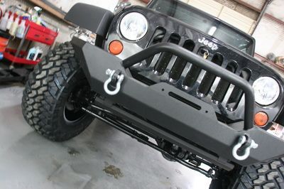 A black jeep with a black bumper is parked in a garage