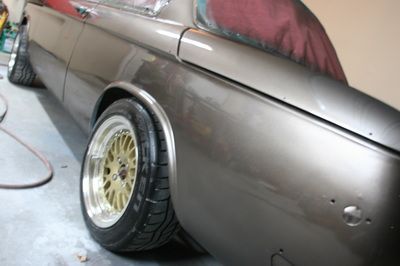A car with gold wheels is parked in a garage