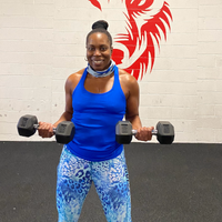 A woman in a blue tank top is holding a pair of dumbbells.