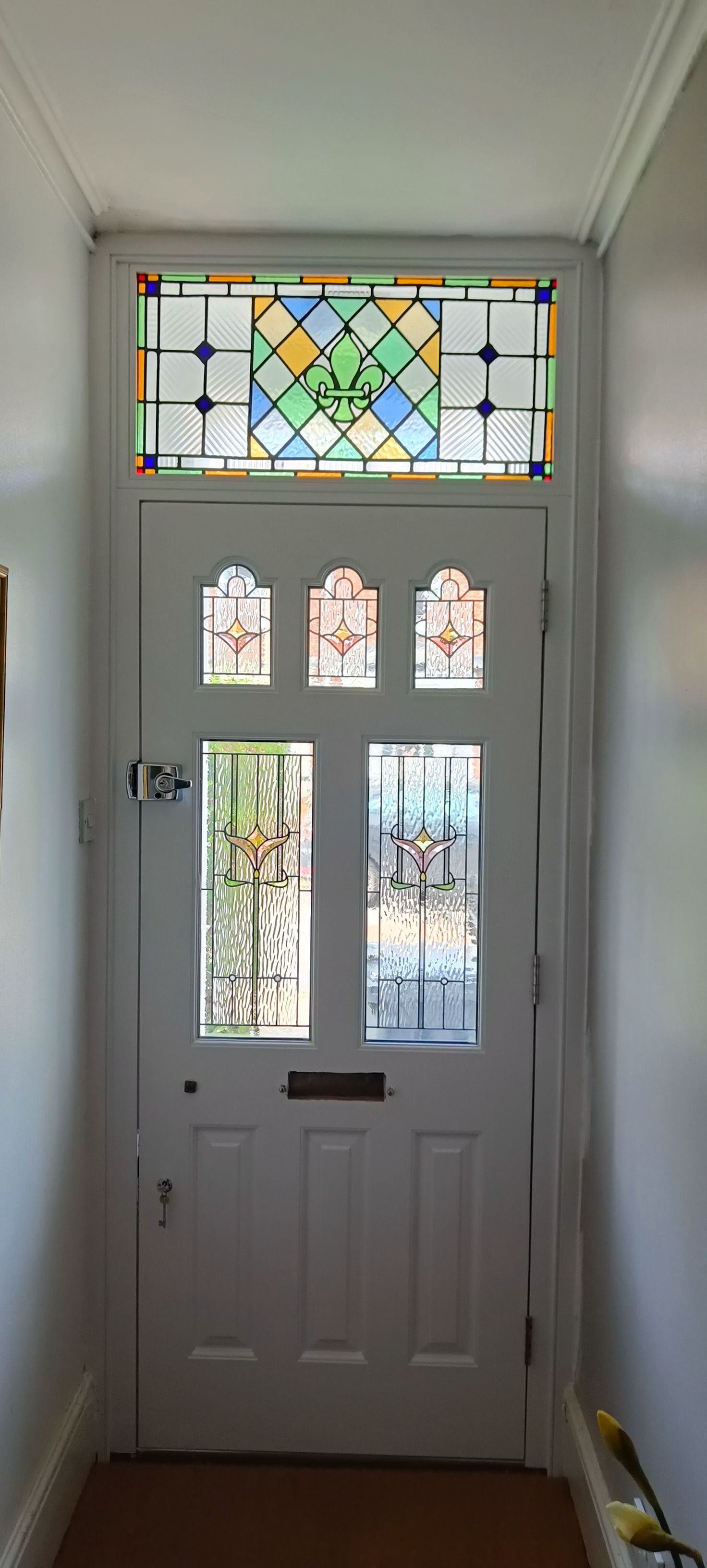 White spray finished timber front door with stained-glass window panels and sidelights in a hallway
