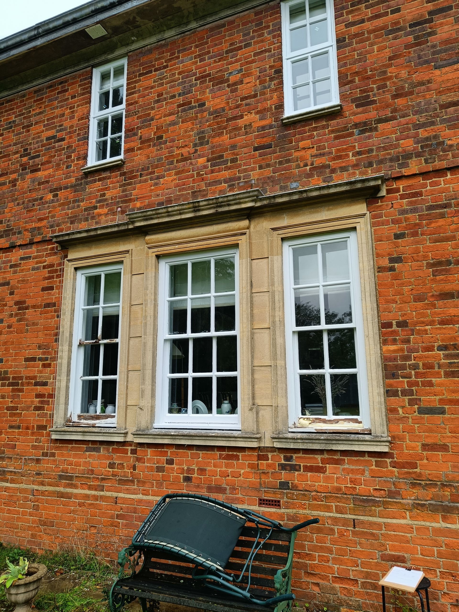 Old listed house with three replacement timber white-framed period sliding sash windows and a bench beneath them