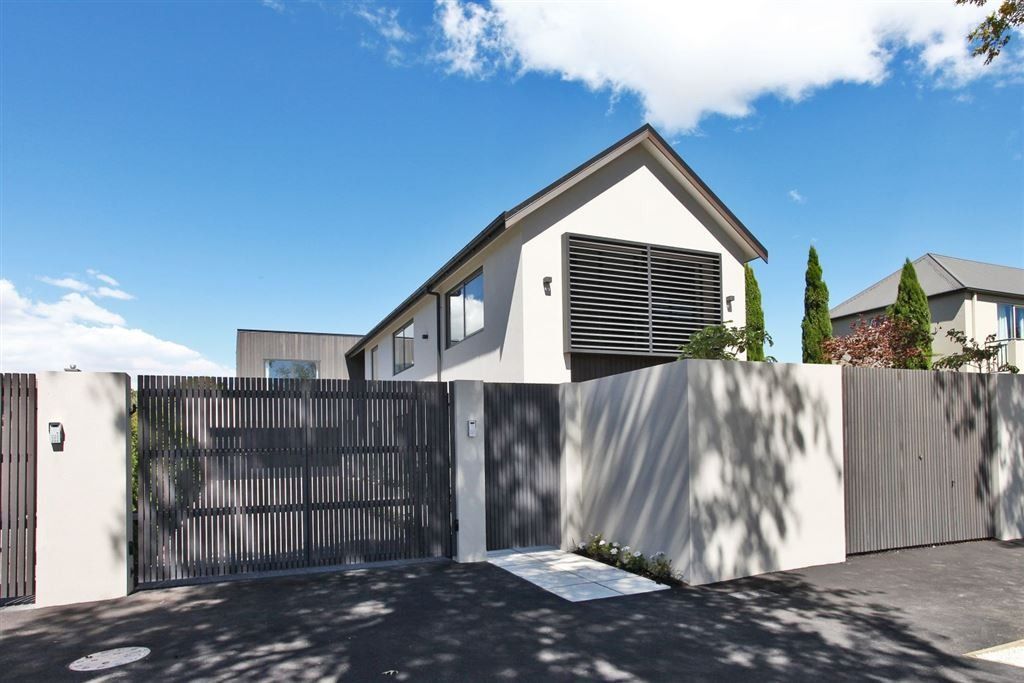 Modern house with gray fencing and gate under a blue sky