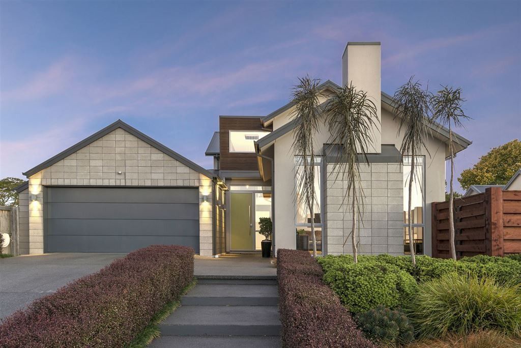 Modern suburban house with a two-car garage, front walkway, and landscaped yard at dusk