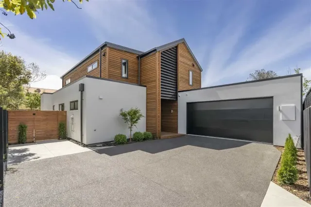 Modern two-story house with wood accents, white exterior, and a large garage driveway