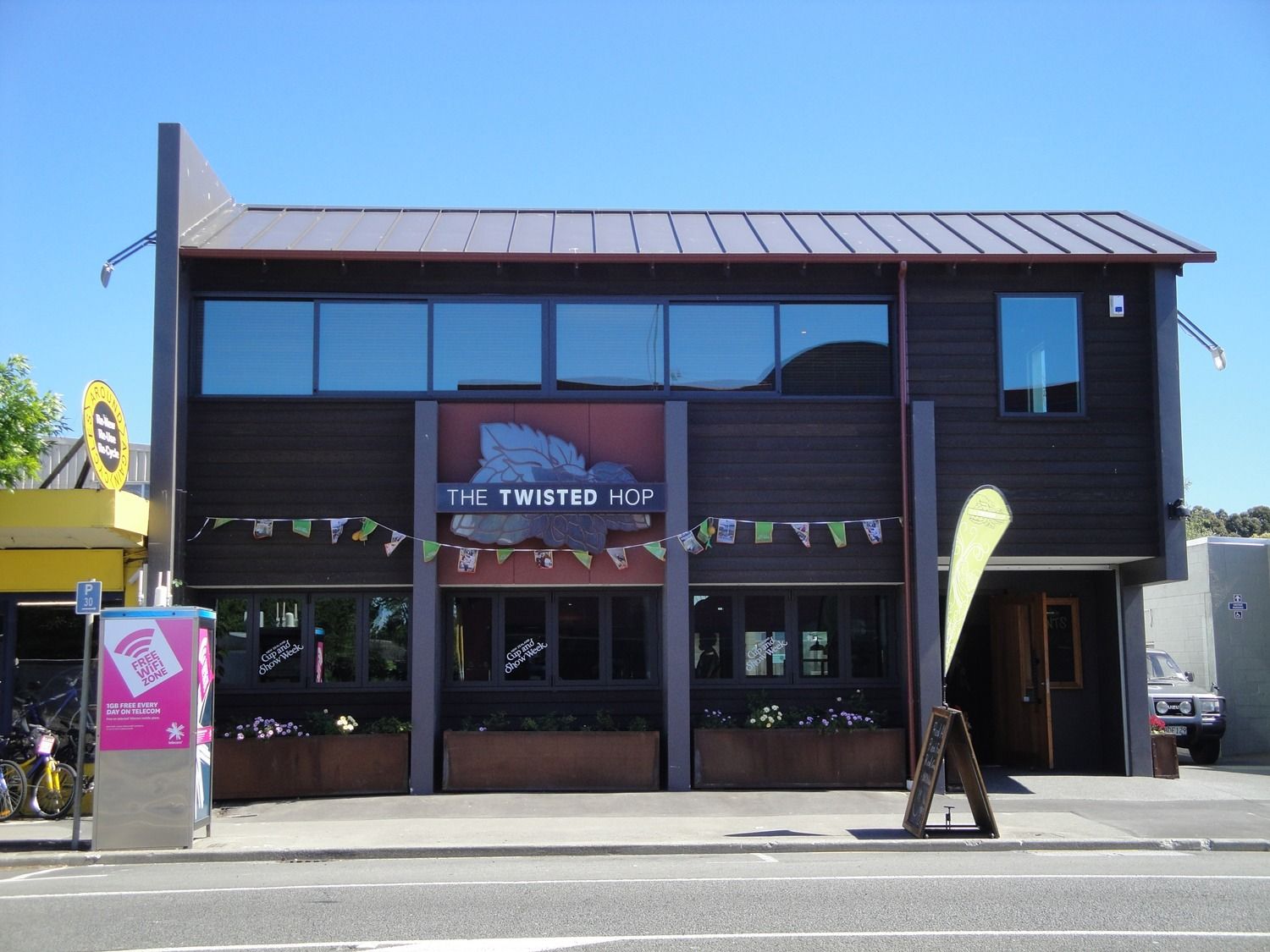 Storefront of The Taste Ice cream shop with dark wood exterior and large windows on a sunny street