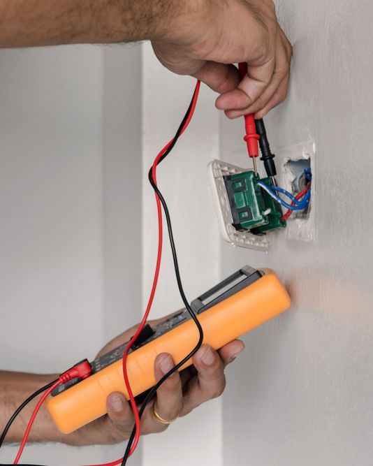 A Person Is Using A Multimeter To Test A Light Switch On A Wall — Steve Mason Electrical In Port Macquarie, NSW
