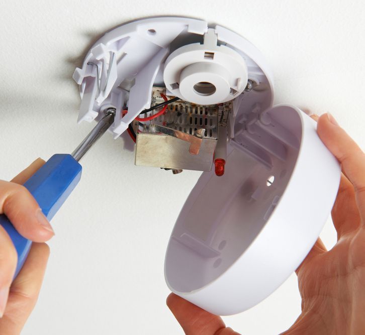 A Person Is Fixing A Smoke Detector With A Screwdriver — Steve Mason Electrical In Port Macquarie, NSW 